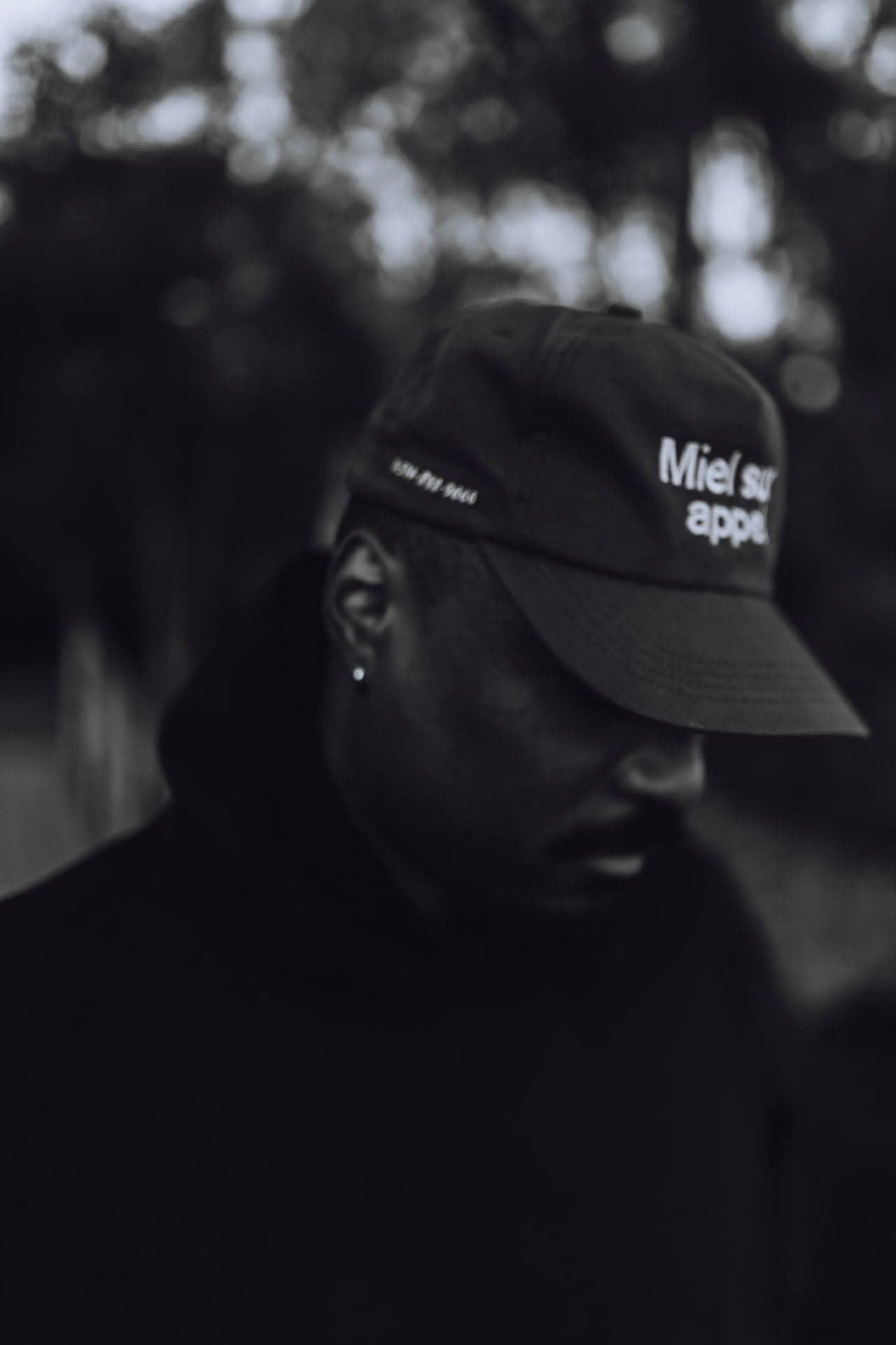 JEFFERY in profile, head bowed under the brim of his cap
